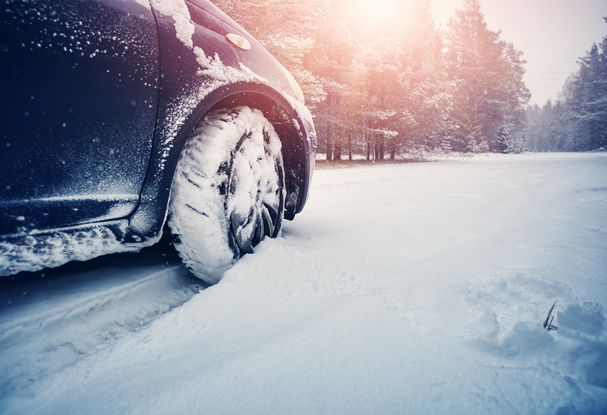 Απεικονίζει ένα αυτοκίνητο με φορεμένες τις χιονοκουβέρτες σε ένα δρόμο με χιόνια